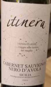 Rotweinflasche Itinera Prima Classe Cabernet Sauvignon Nero d'Avola mit dunklem Etikett und weißer Schrift vor hellem Hintergrund.